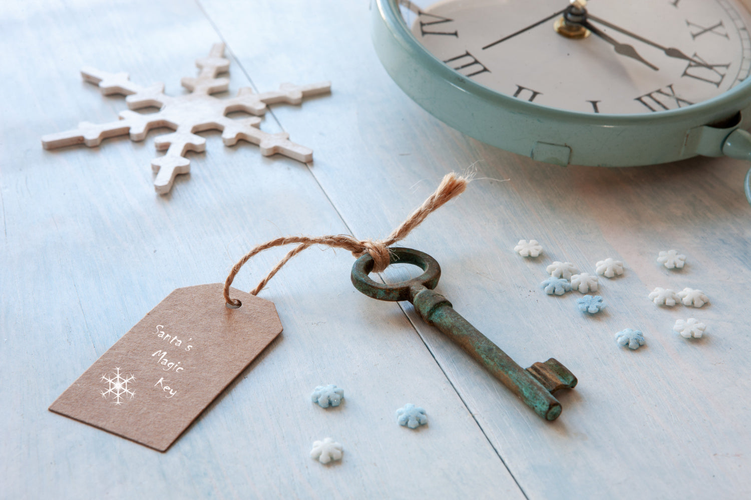 Close-up of Santa's magic key on a light blue wooden background, amidst Christmas decorations.