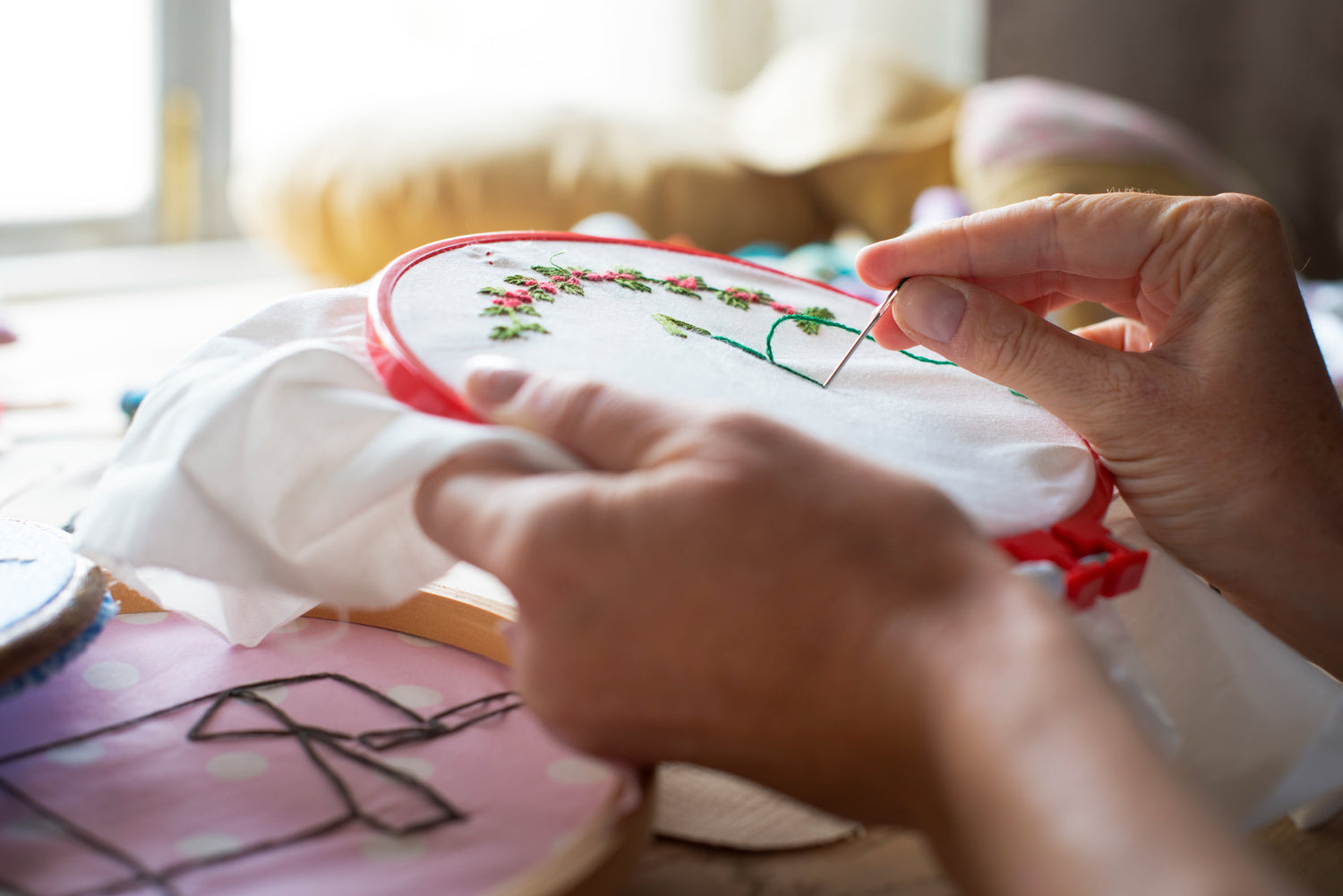 Close-up of hands sewing embroidery, showcasing the art of handicraft and handmade creativity.