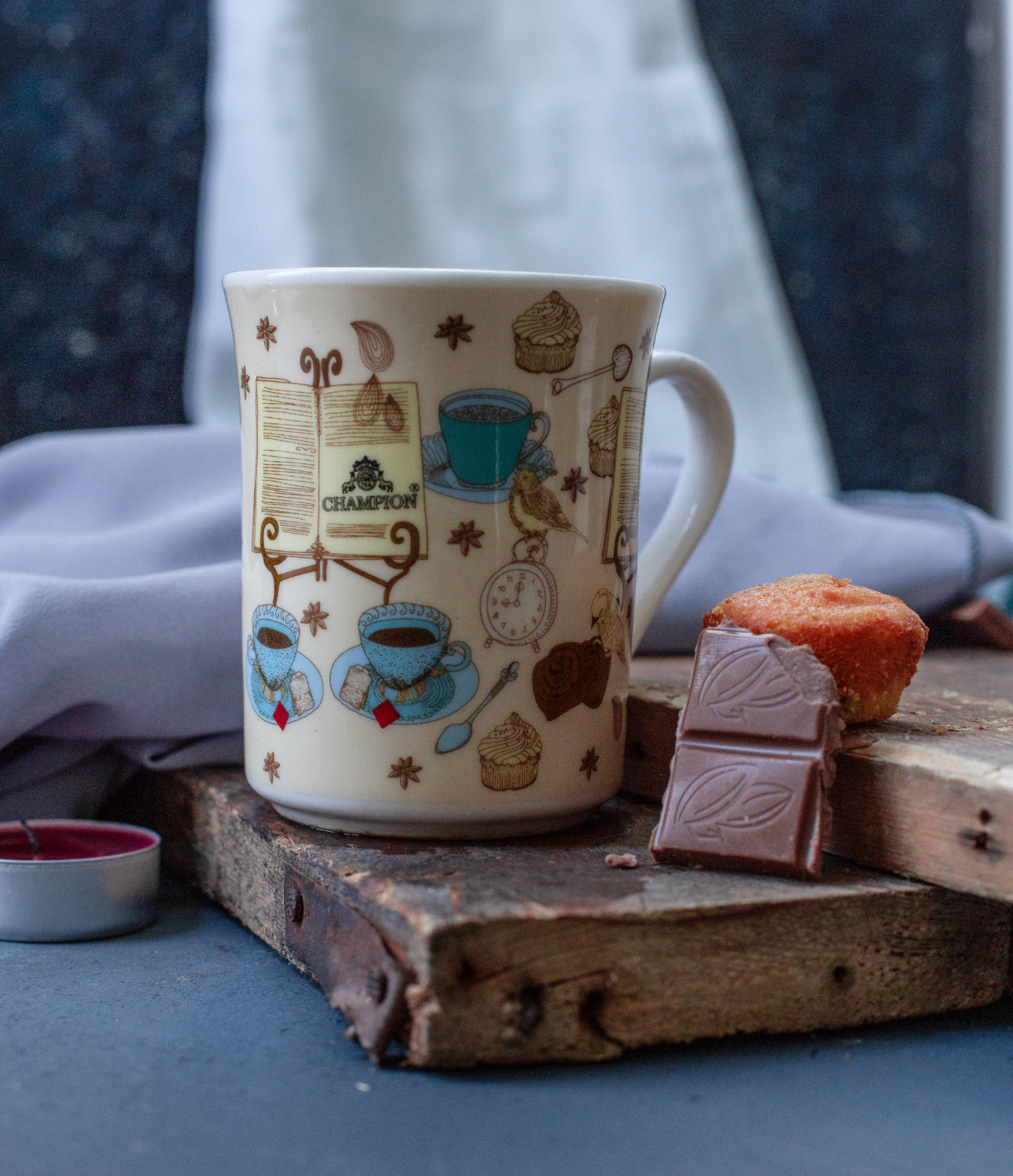 Cup of drink beside a chocolate bar and muffin on a wooden surface.