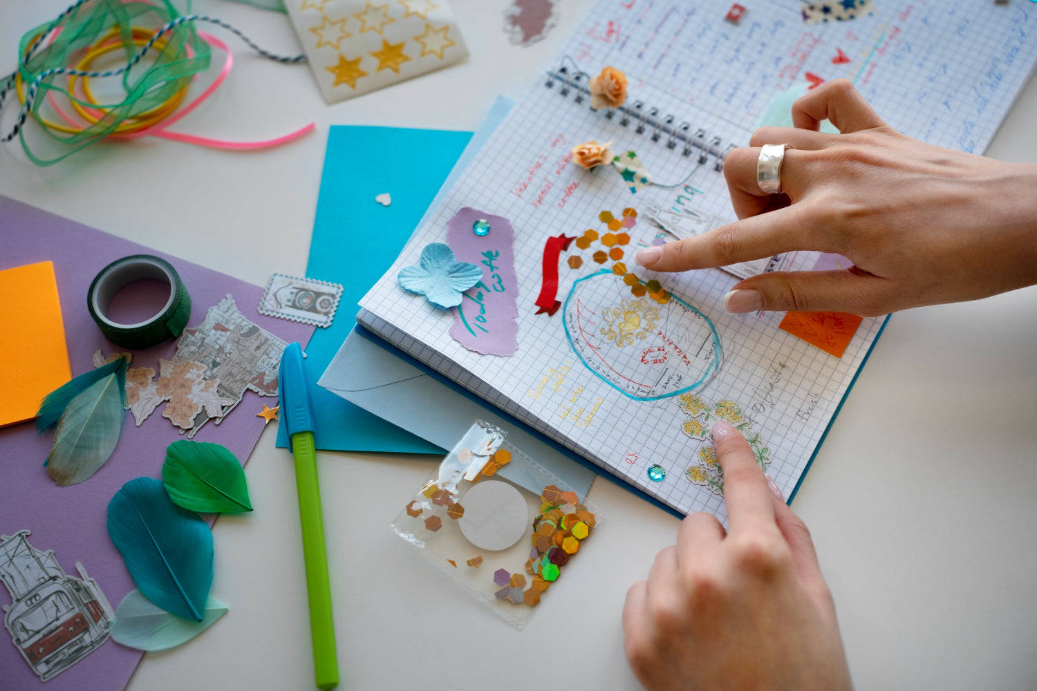 A creative woman engaged in high-angle journaling with various art supplies.