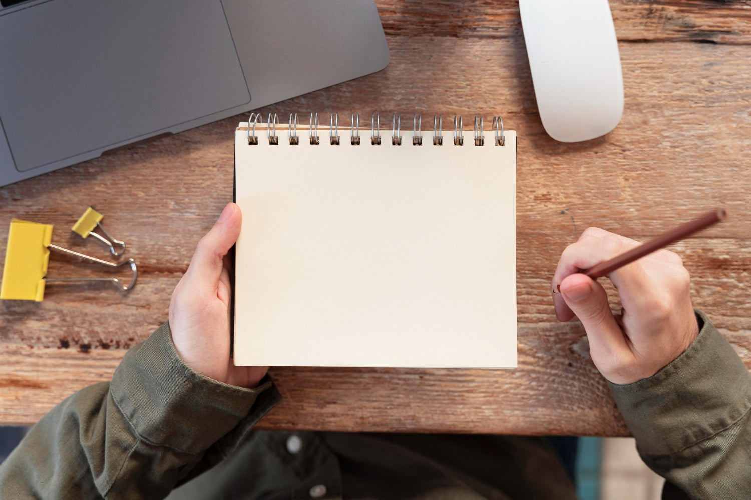 Top view of a freelancer jotting down notes on a notepad.